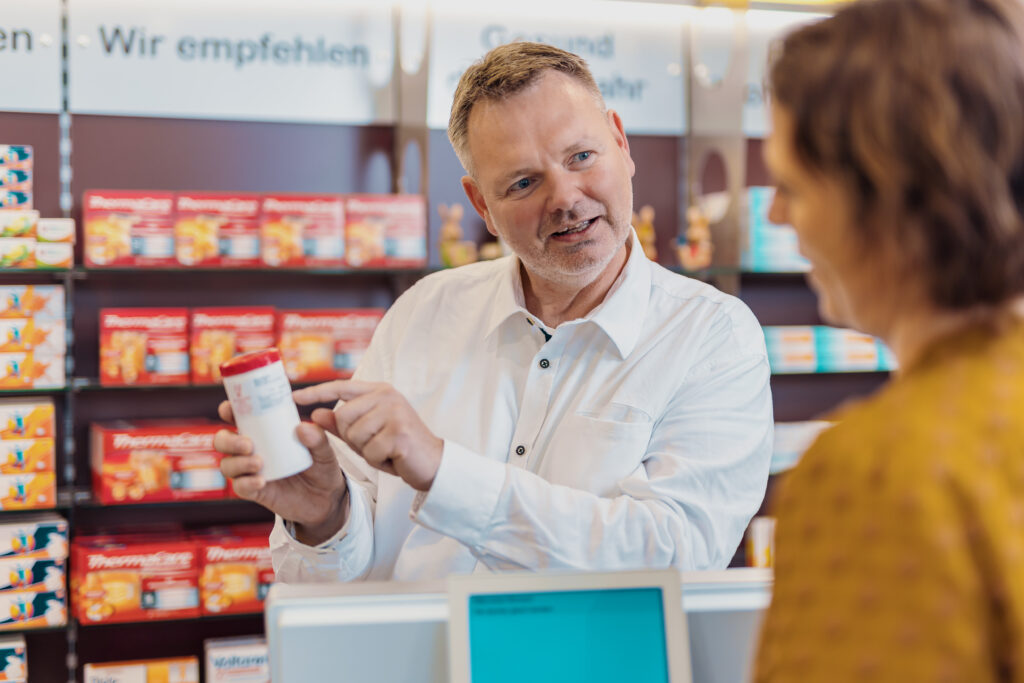 Ein Apotheker erklärt einer Kundin ein Medikament
